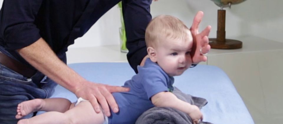 Training der Bauchlage im Säuglingsalter über einer Handtuchrolle